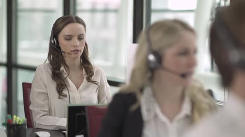 Kaukasische Frau arbeitet in einem attraktiven modernen Call Center (2 von 4)