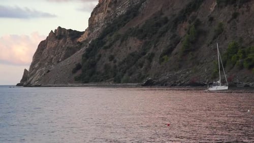 Small Boat Docked on Rocky Beach at Sunset
