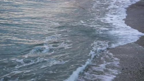 Waves Gently Crashing on Rocky Gray Beach