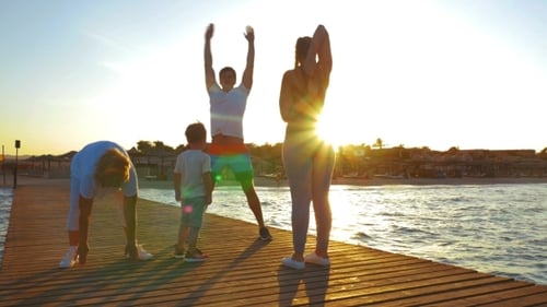 Familie trainiert auf dem Pier bei Sonnenuntergang