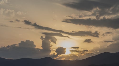 Sunset Over Hill and Fluffy Clouds