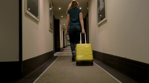 Woman With Suitcase Walking In Hotel Corridor