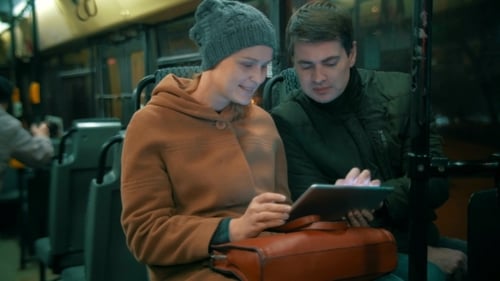 Woman Using Tablet with Friend on Night Bus Ride