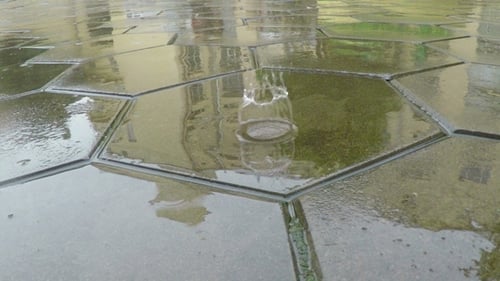 Regentropfen fallen auf Steinplatten.