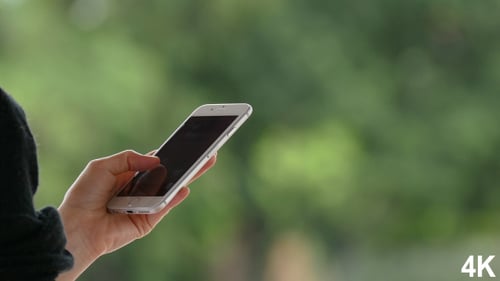 Person Using a Silver Phone with a Green Background