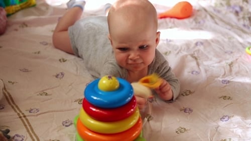Happy Baby Playing With Colorful Toys On Blanket