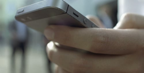 Hand Holding Cellphone Device in Urban Setting