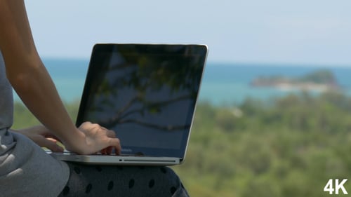 Woman Working on Laptop with Tropical Ocean View