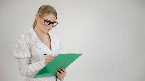 Woman Writing on Green Clipboard in Office