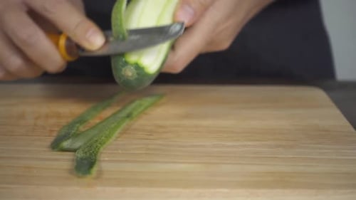 woman making salad healthy food and chopping cucumber on cutting board in the kitchen.