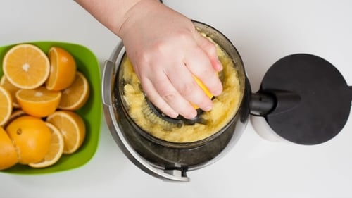 Woman's Hand Making Orange Juice Using a Juicer