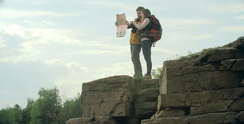 Couple Hiking With Backpacks Consults Map on Overlook