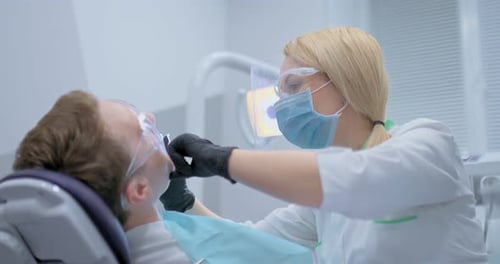 Female Dentist Examines the Patient's Teeth and Treats Caries