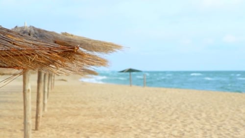 Straw Umbrellas On The Coast Of The Blue Sea.