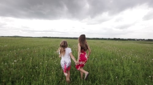 Young Girl Running In a Field Holding Hands