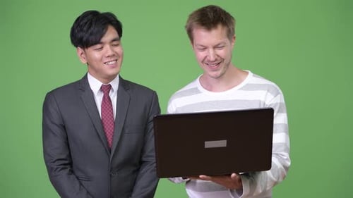 Two Men Using Laptop in Front of Green Screen