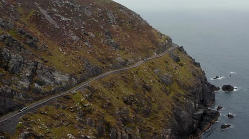 Breath Taking Shot of Slowly Moving Car on Narrow Panoramic Route in Steep Slope Above Sea Coast