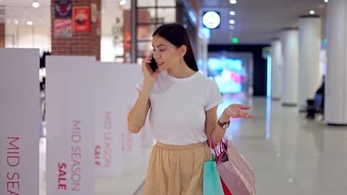 Woman Talking on Mobile Phone with Friend During Shopping Day in Mall