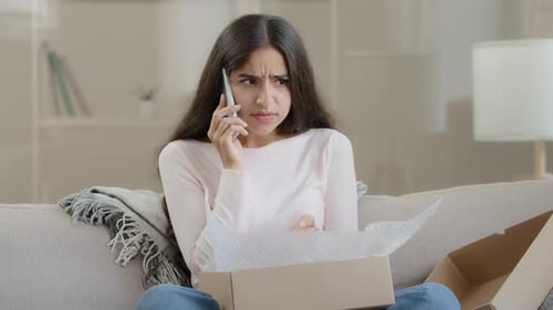 Young Woman Talking on Phone Opening Package
