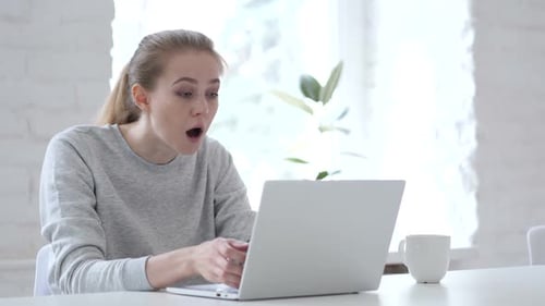 Woman Typing on Laptop Looking Surprised