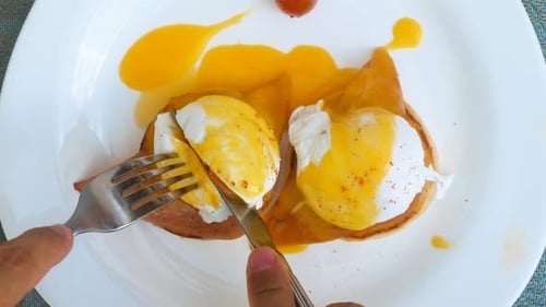Cutting Into Delicious Eggs Benedict for Breakfast