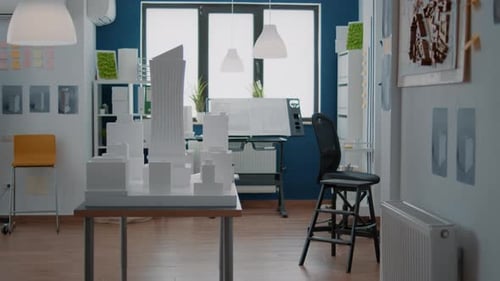 Leeres Technisches Büro mit Immobilienbauplan und Gebäudemodell auf dem Schreibtisch