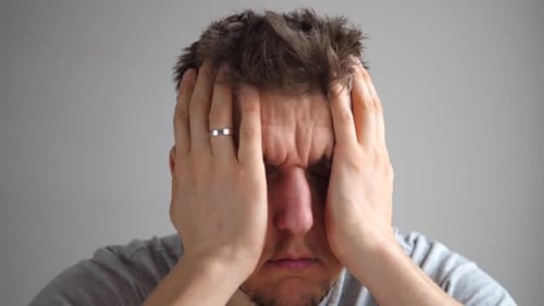 Man Rubs Temples Expressing Stress and Fatigue
