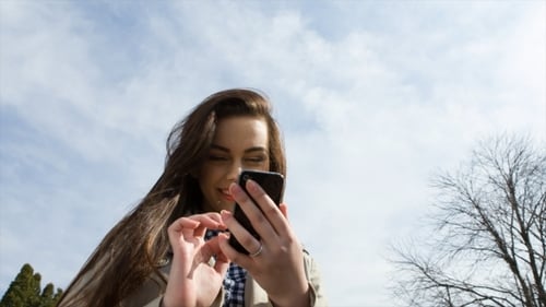 Woman Holding Cell Phone In Park.