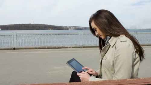 Woman Using Tablet Device by River on Sunny Day