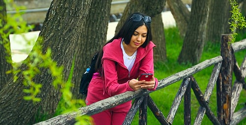 Young Woman Talking On The Phone Outdoors In a Park