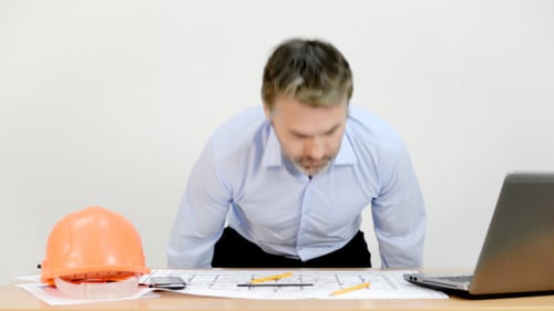 Architect Drawing on Plans at Desk