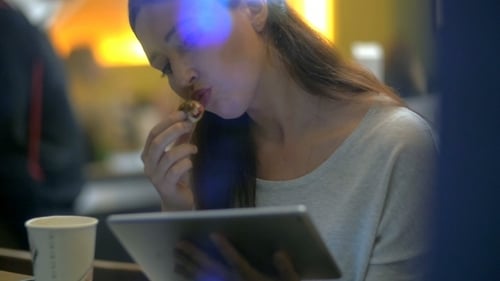 Brunette Woman Eats Cake While Reading On