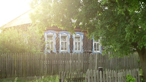 Rustic Wooden House Behind Weathered Fence