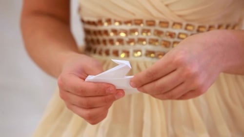 Hände Mädchen machen Origami-Kranich.