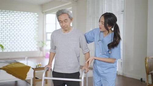 Senior Man Walking with Nurse's Assistance Indoors