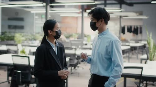 Two Happy Japanese Colleagues Talking Wearing Face Masks In Office
