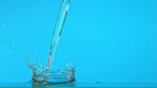 Super Slow Motion of the Jet of Water Falls on a Blue Background