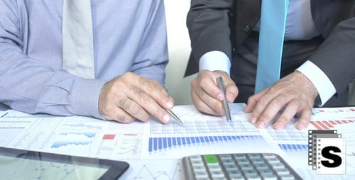 Business Men Analyzing Financial Documents in Office