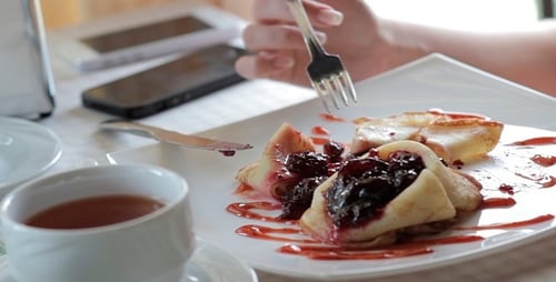 Pancakes with Berry Sauce Being Eaten with Tea