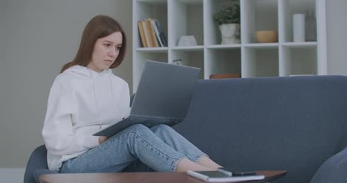 Woman using laptop on sofa at home