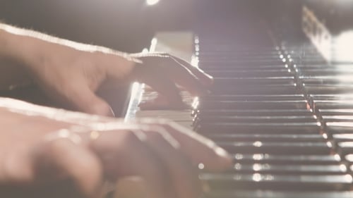Hands Playing Piano Keys in Bright Light