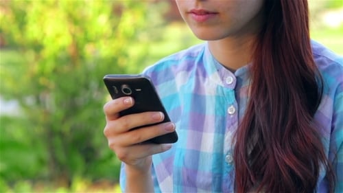 Beautiful Smiling Young Woman Using Mobile In Park