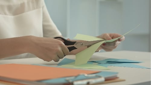 Woman Is Cutting Green Paper Using Scissors