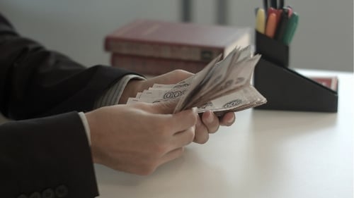 Man Counting Money on a Desk
