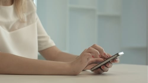 Woman Using Smartphone at Table Indoors