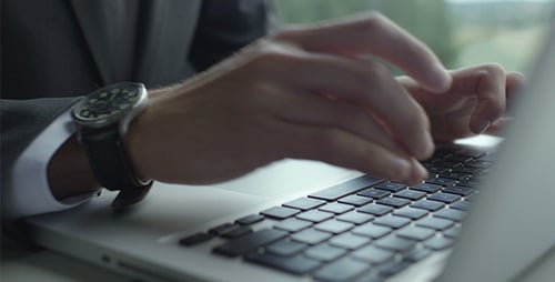 Man Typing on Laptop Computer in Office