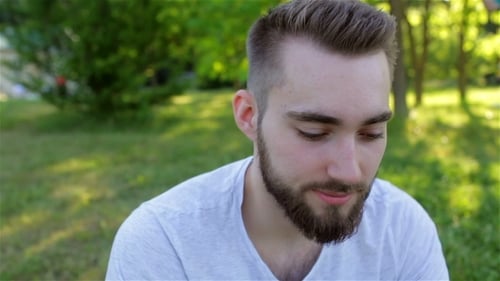 Casual Young Man Using a Phone In The Park