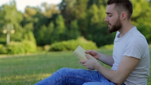 Junger Mann liest ein Buch auf dem Rasen