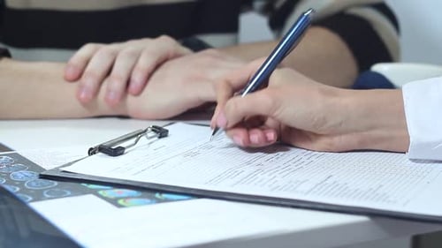 Doctor Filling Out Patient Medical Form at Desk