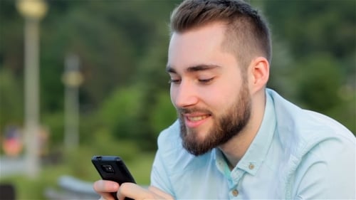 Young Man With Mobile Phone In Park